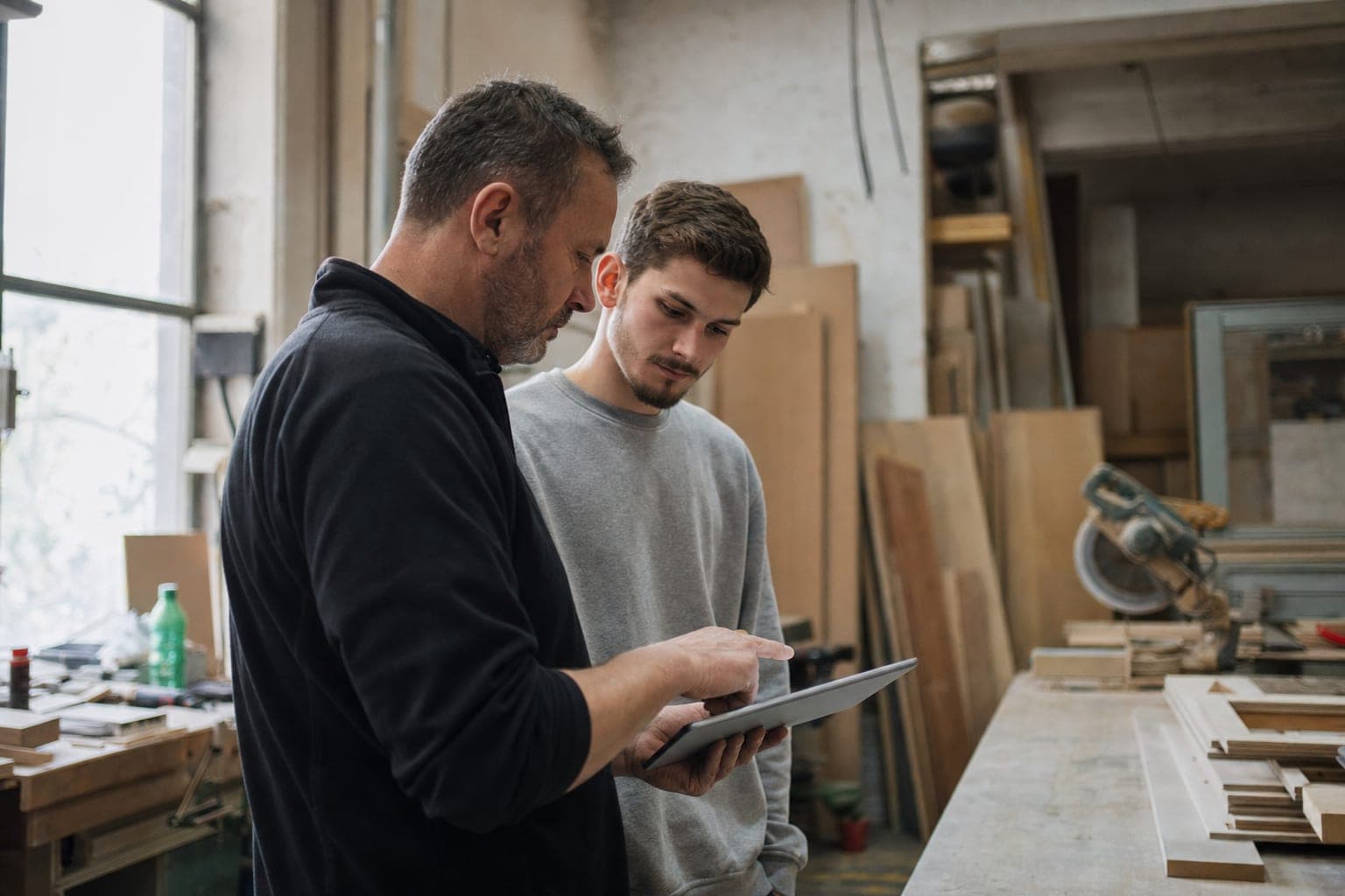 Betriebsinhaber und neue Fachkraft am Tablet in der Werkstatt